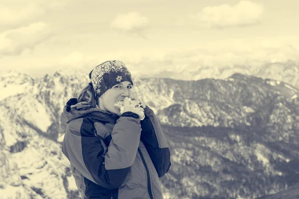 Женщина-альпинистка ест сэндвич в заснеженных горах . — стоковое фото