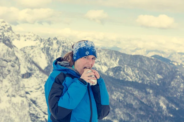 Karla kaplı dağlarda sandviç yiyen dişi dağcı.. — Stok fotoğraf