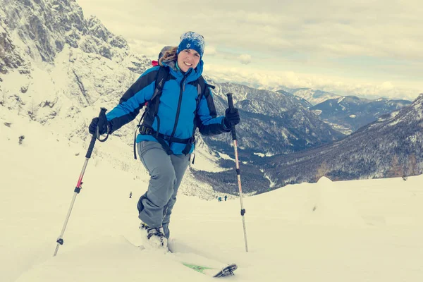 Female ski tourer ascending snow covered mountain slope. — Stock Photo, Image