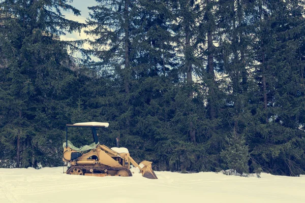 Oude bulldozer geparkeerd op besneeuwde weide bedekt met sneeuw. — Stockfoto