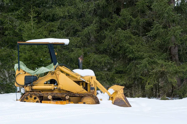 Old bulldozer parked on snowy meadow covered with snow. — Stock Photo, Image