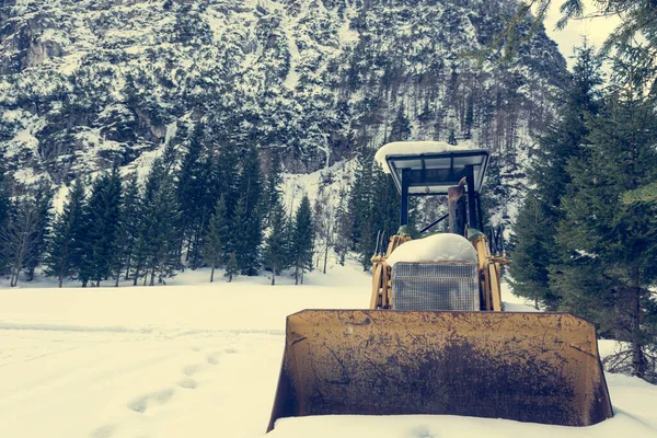 Vecchio bulldozer parcheggiato su un prato innevato coperto di neve . — Foto Stock
