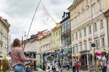 Ljubljana, Slovenya - 19 Haziran 2016: Şehir merkezinde birçok baloncukla gösteri yapan sokak sanatçısı.