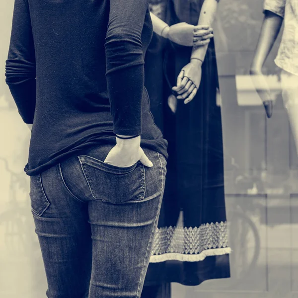 Vista trasera de una mujer descansando su mano en el bolsillo mientras hace compras en la ventana . — Foto de Stock