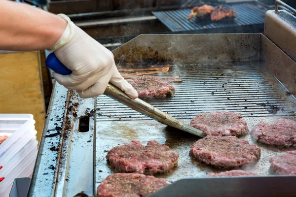 Chef preparing delicious burgers and flipping them on grill. — Stock Photo, Image