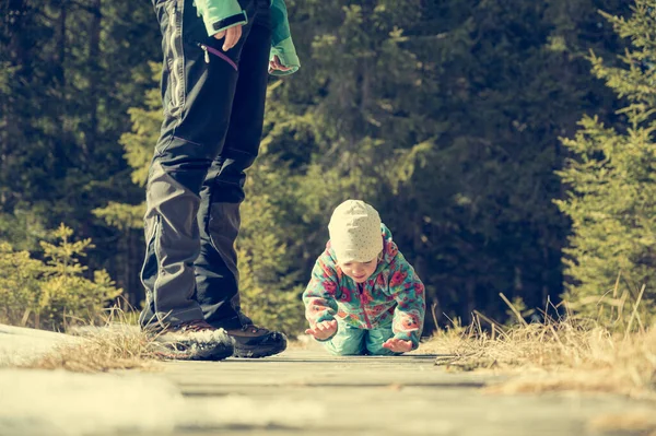 Menina bonito rastejando em um calçadão em correr através da floresta de inverno . — Fotografia de Stock