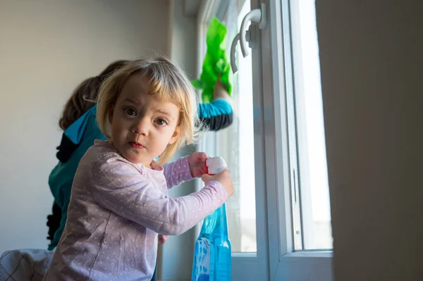 Söt flicka som hjälper mamma att rengöra fönster. — Stockfoto