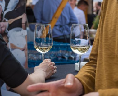 Şarap bardakları tutan bir çiftin açık havada içerkenki görüntüsü..