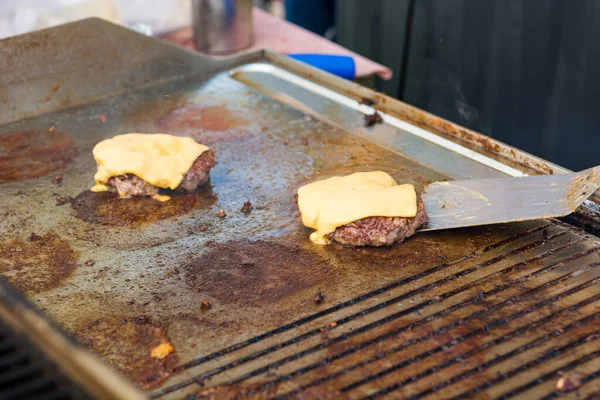 Chef preparare deliziosi hamburger di formaggio e capovolgerli sulla griglia . — Foto Stock