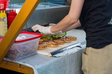 Aşçı lezzetli hamburgerler hazırlıyor - büfenin yanından manzara.