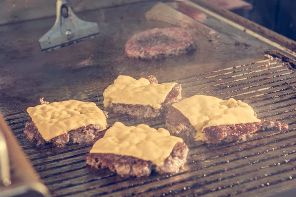 Chef preparare deliziosi hamburger di formaggio e capovolgerli sulla griglia . — Foto Stock