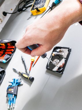 Repairing malfunctioned computer hard drive - removing screws and disassembling it.