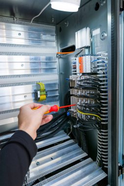 Elektrik mühendisi elektrik kabinini kontrol ediyor ve bağlantı şeritlerini tamir ediyor.