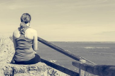 Aktif kadın oturuyor ve deniz manzarasının tadını çıkarıyor. Hayatı yaşamak ve meditasyon yapmak.