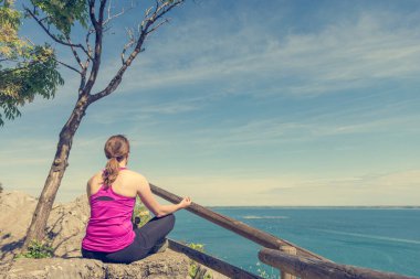 Aktif kadın oturuyor ve deniz manzarasının tadını çıkarıyor. Hayatı yaşamak ve meditasyon yapmak.