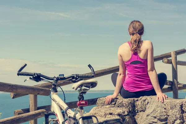 Female cyclist taking a rest and enjoying sea view. Living life. — Stock Photo, Image