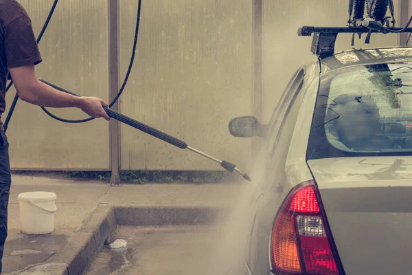 Ein Mann wäscht ein Auto in einer Waschanlage. — Stockfoto