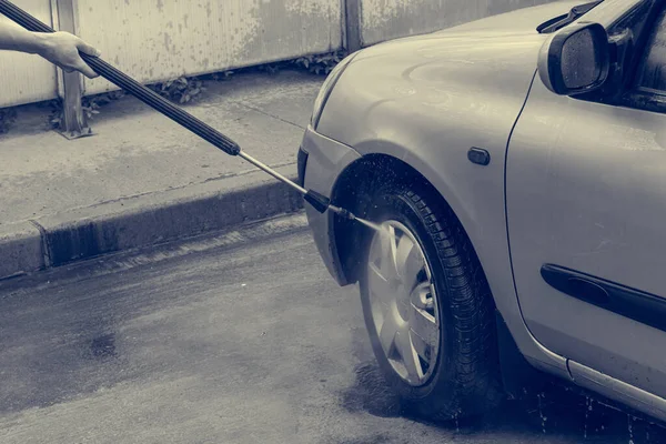 Ein Mann wäscht ein Auto in einer Waschanlage. — Stockfoto