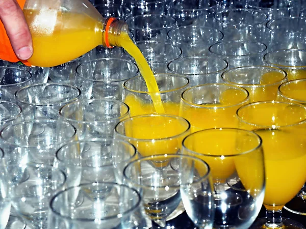 Een gele frisdrank uit een transparante fles wordt in glazen gegoten — Stockfoto