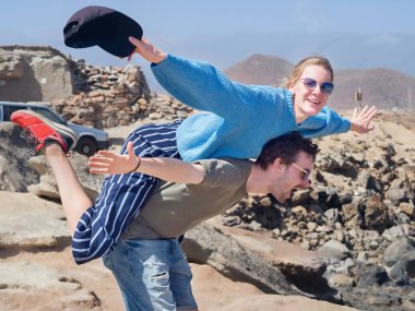 Junges Liebespaar in der Natur, Young lovers in nature, he carries her on his back in the position of a plane.     