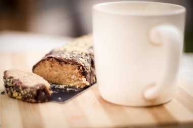 Rollo de nuez baado en chocolate junto a taza de cafe