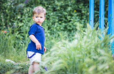 Sevimli sarışın çocuk ayakta duruyor, kafası karışmış görünüyor. Evrensel Çocuk Günü