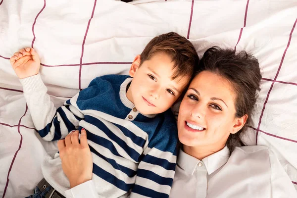 Mom and her son lying in bed, enjoying their time together. — Stock Photo, Image