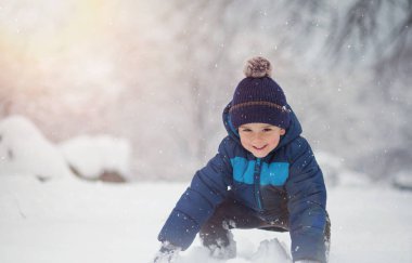 Sevimli, sevimli çocuk neşeyle karla oynuyor. Kış zamanı, çocuk aktiviteleri.