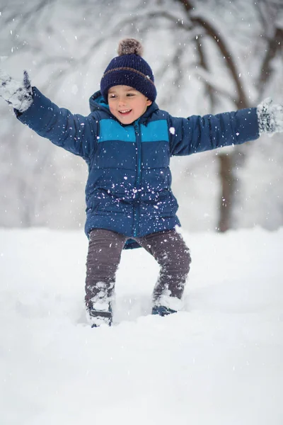 可爱可爱的男孩兴高采烈地与雪玩耍. 冬天，孩子们的活动 — 图库照片