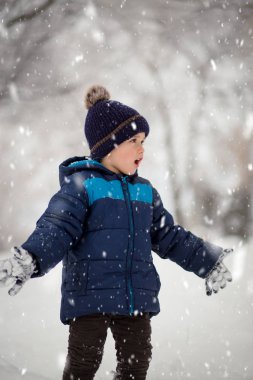 Sevimli, sevimli çocuk neşeyle karla oynuyor. Kış zamanı, çocuk aktiviteleri.