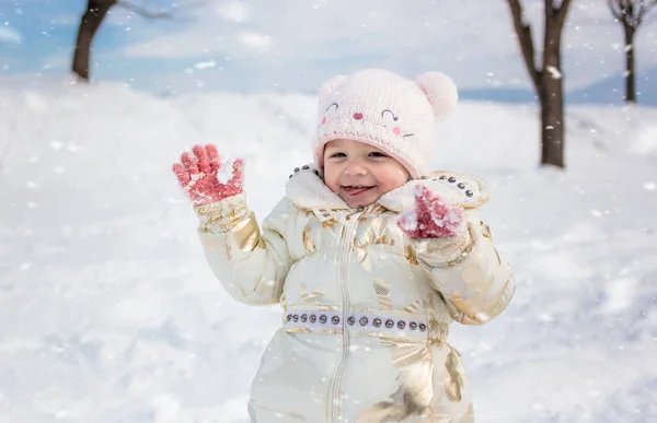 Menina em jaqueta branca se divertindo, brincando fora, cercada de neve . — Fotografia de Stock