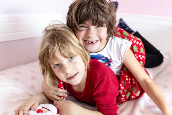 Милі, маленькі сестри лежать на ліжку у своїй кімнаті в різдвяному вбранні. Відпочинок — стокове фото