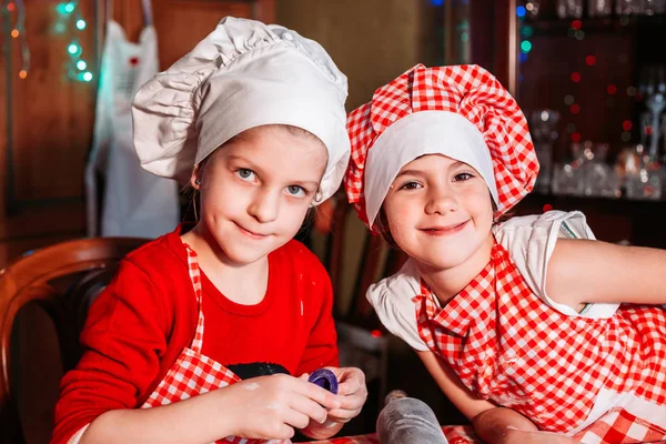 Mignonnes, petites filles en uniforme de chef avec tablier et chapeau faisant des biscuits au gingembre . — Photo