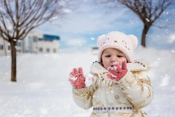 Kleines Mädchen in weißer Jacke hat Spaß, spielt draußen, umgeben von Schnee. — Stockfoto