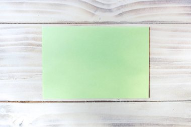 Ahşap arka planda boş bir yeşil kağıt parçası. Doku, boş yazma alanı