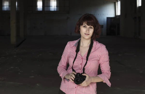 Girl photographer holding camera inside an factory building. Vintage, grainy