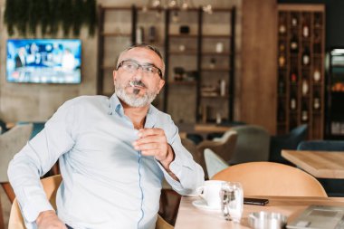 İlk sabah kahvesini içip, sigara içen bir adam bir kafede mola veriyor..