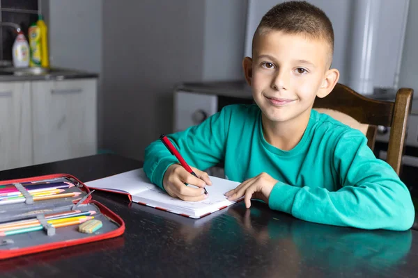 Cute boy in green sweatshirt writing his homework. Kids and school concept — Stock Photo, Image