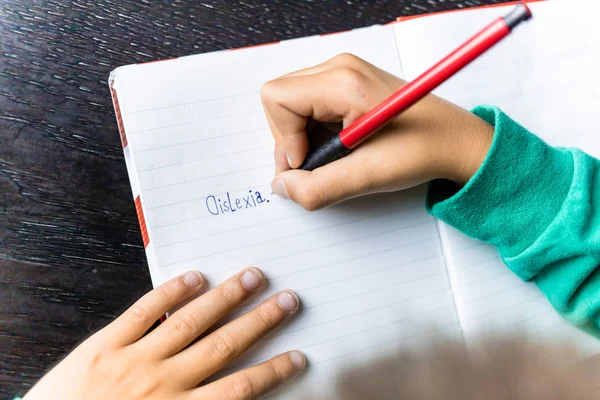 Boy writing dyslexia in his notebook, wrong spelling. Learning disorder — Stock Photo, Image