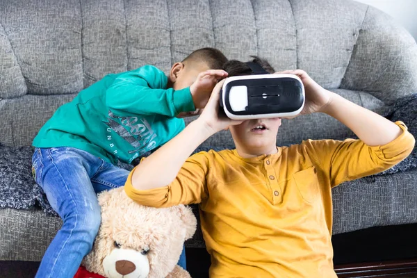 stock image Boy having fun with vr headset with his brother next to him and teddy bear