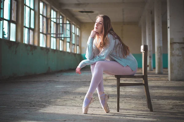 Photo of ballerina while shes sitting on the chair in an old building. — Stock Photo, Image