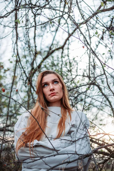 Girl in straitjacket, outside in the woods, branches surrounding her. — Stock Photo, Image