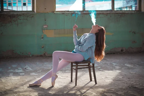 Ginger, blonde ballerina sitting on the chair smoking. Sport and smoking concept