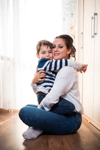 Beautiful young mom and her son hugging each other tightly. — Stock Photo, Image