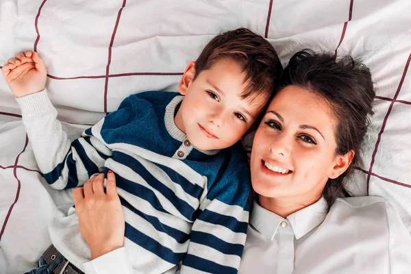 Young mom having great time with her son in bed. Playing around and smiling — Stock Photo, Image