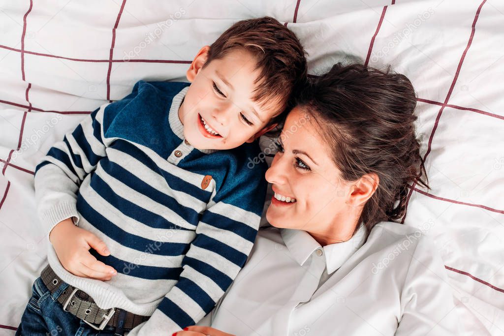 Mom having great time with her son in bed. Playing around and smiling.
