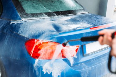 Man washing his car in car wash self service shop. Car maintenance concept