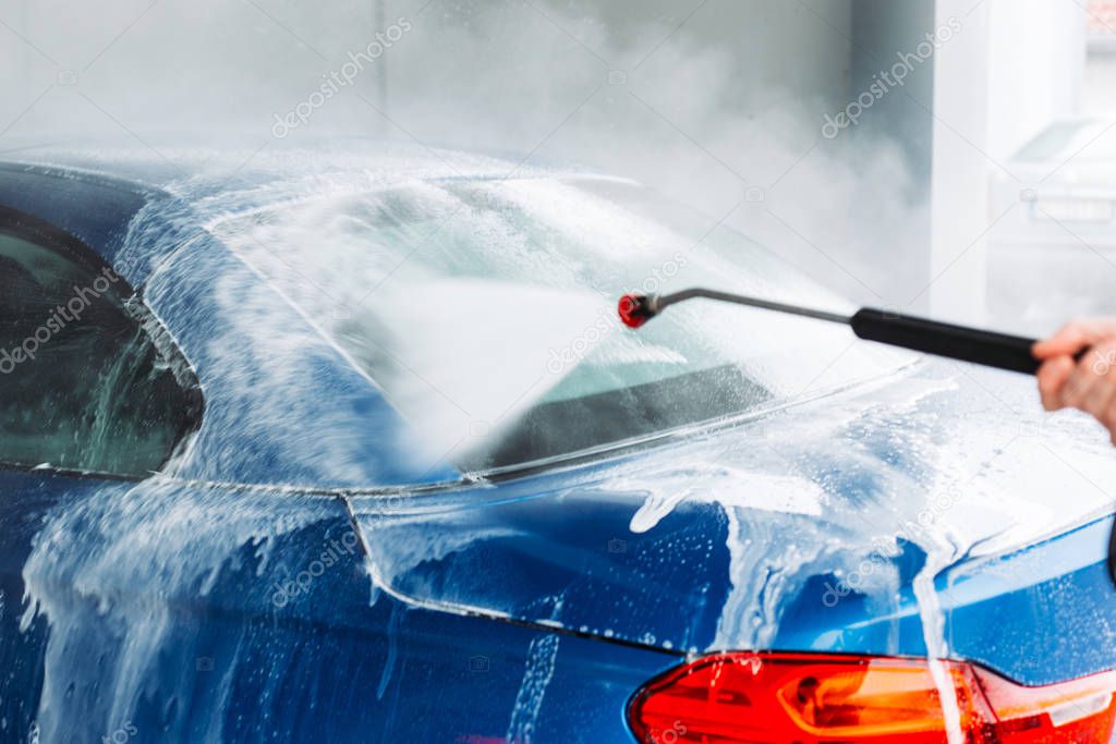 Man washing his car in car wash self service shop. Car maintenance concept