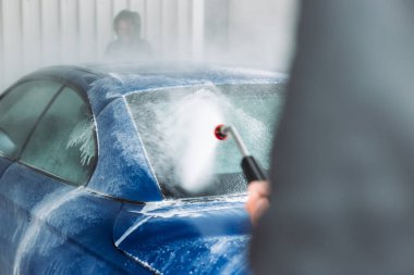 Man washing his car in car wash self service shop. Car maintenance concept