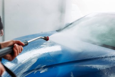 Man washing his car in car wash self service shop. Car maintenance concept